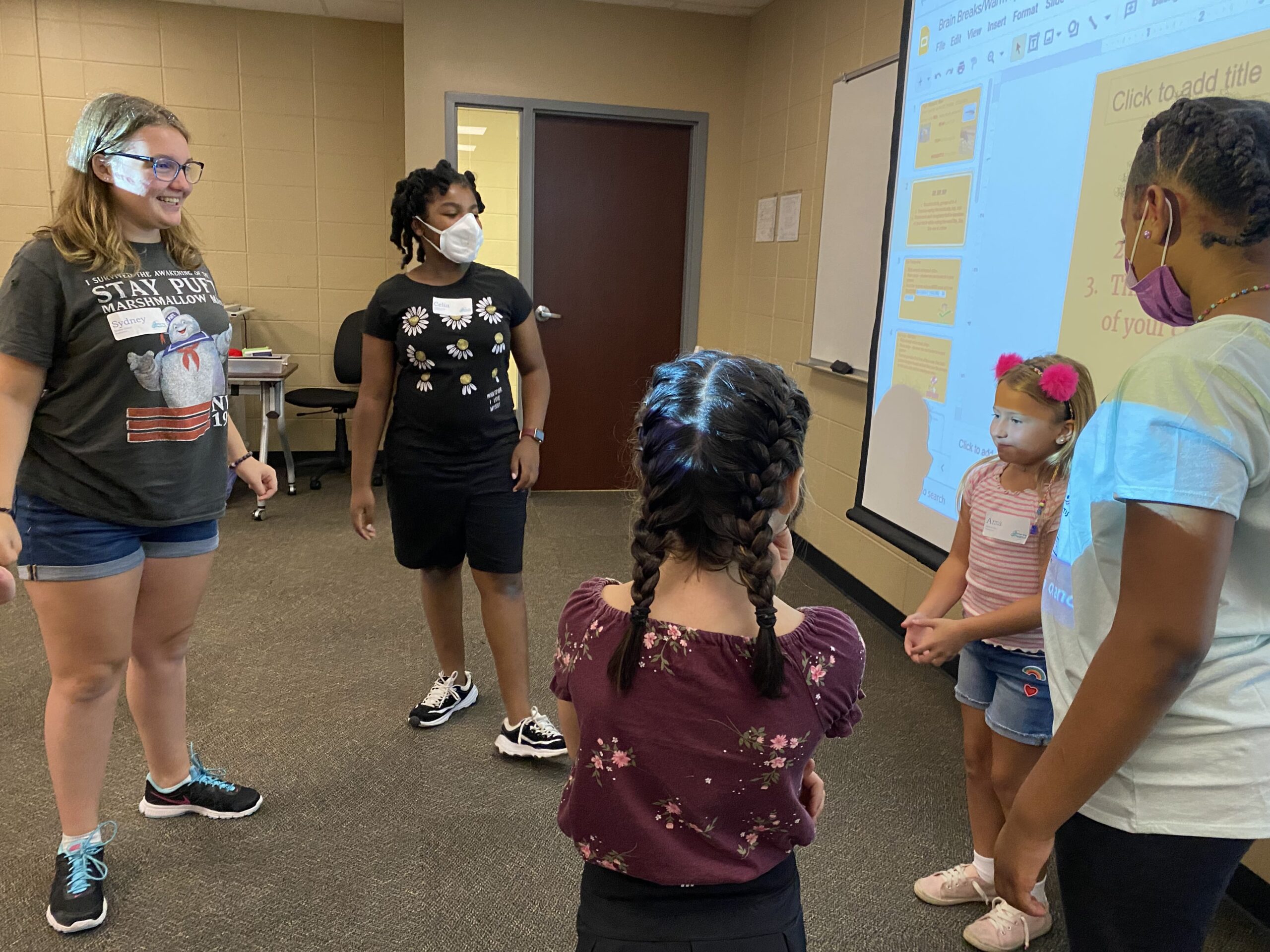 Multiple kids and mentors gathered around a digital board at After The Peanut's STEAM Camp